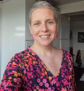 A woman with short hair wearing a colorful floral top, smiling