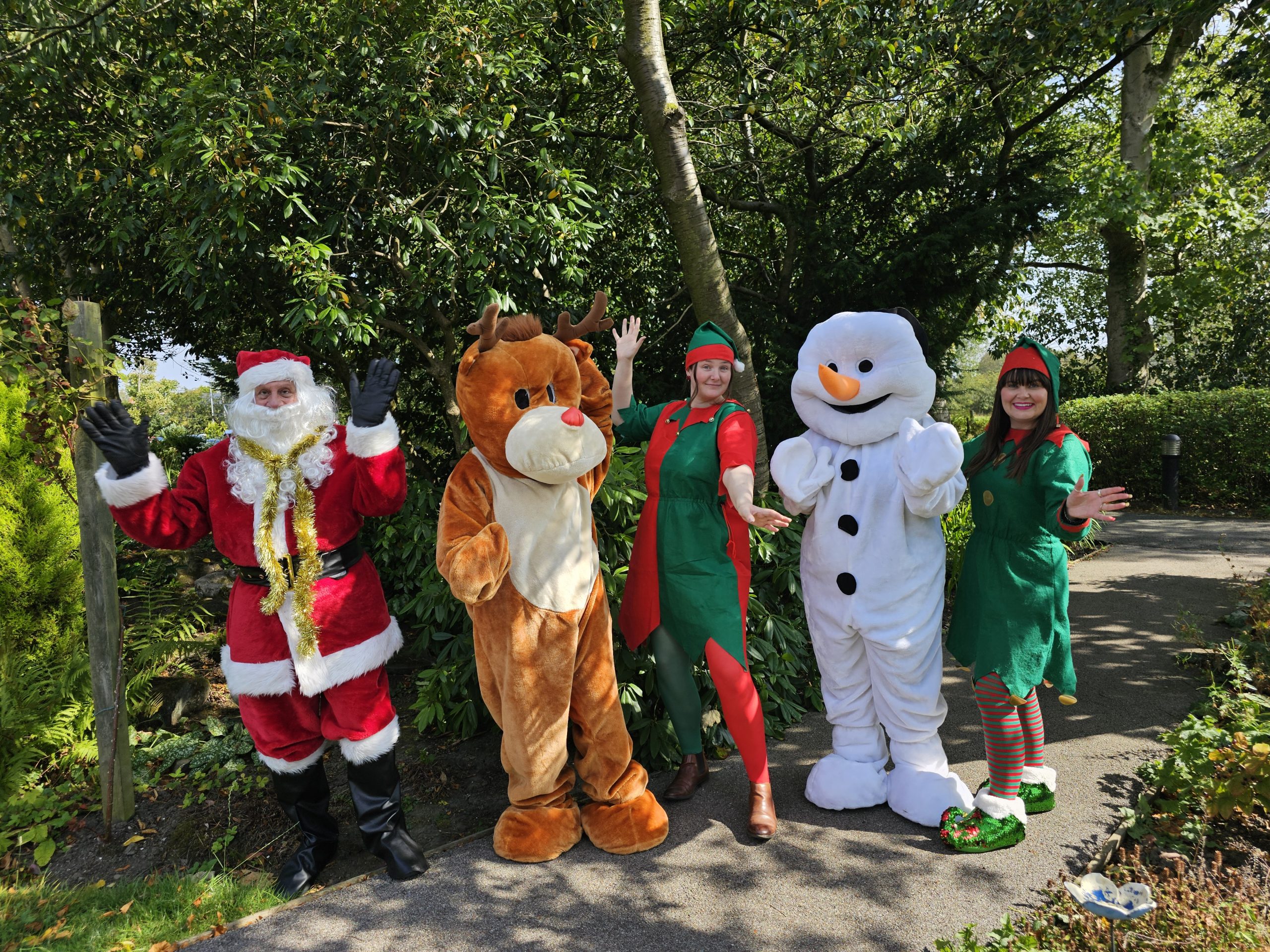 festively dressed characters (people) wave at the camera