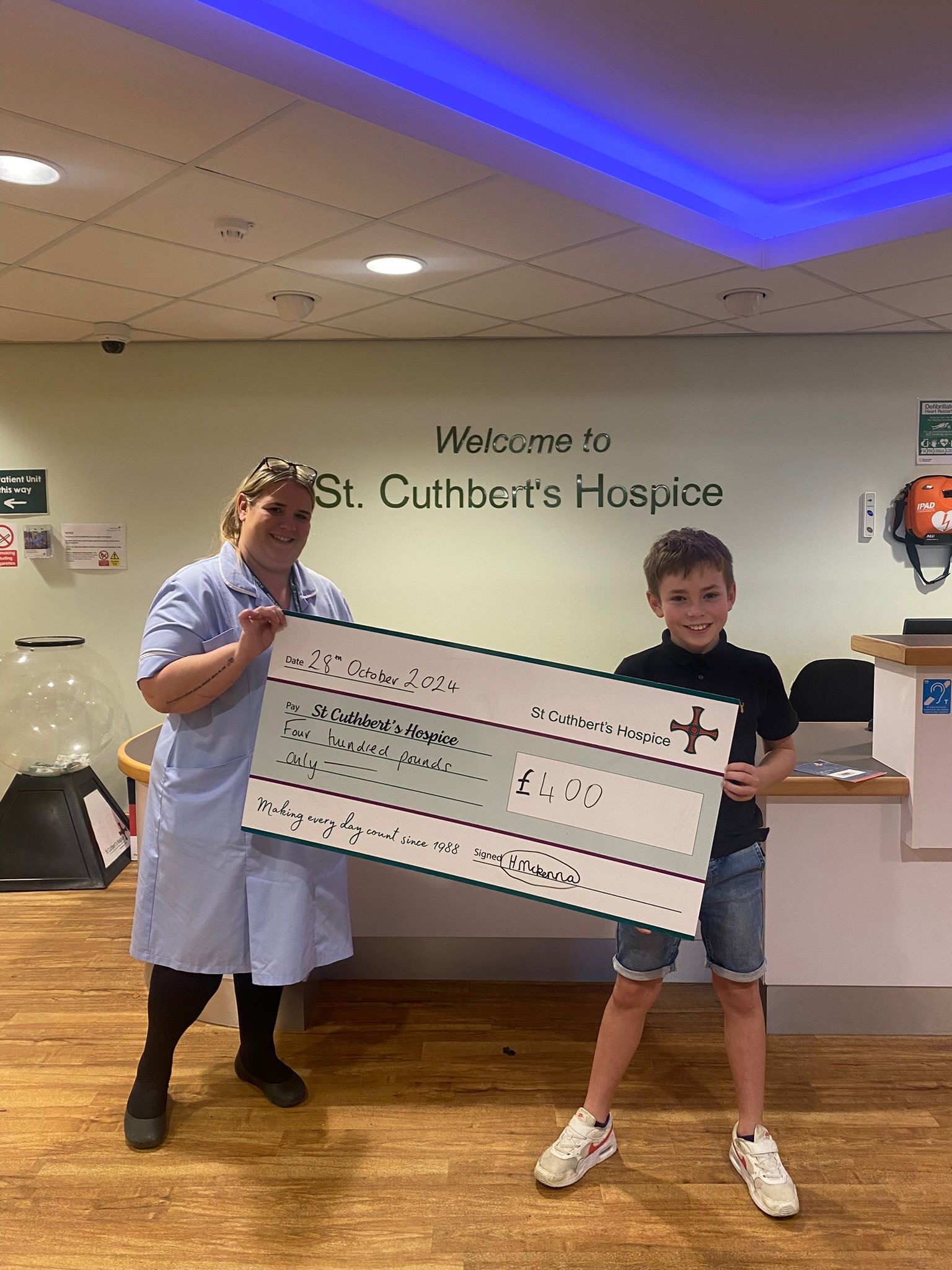 a woman and child holding a giant cheque smiling at the camera 