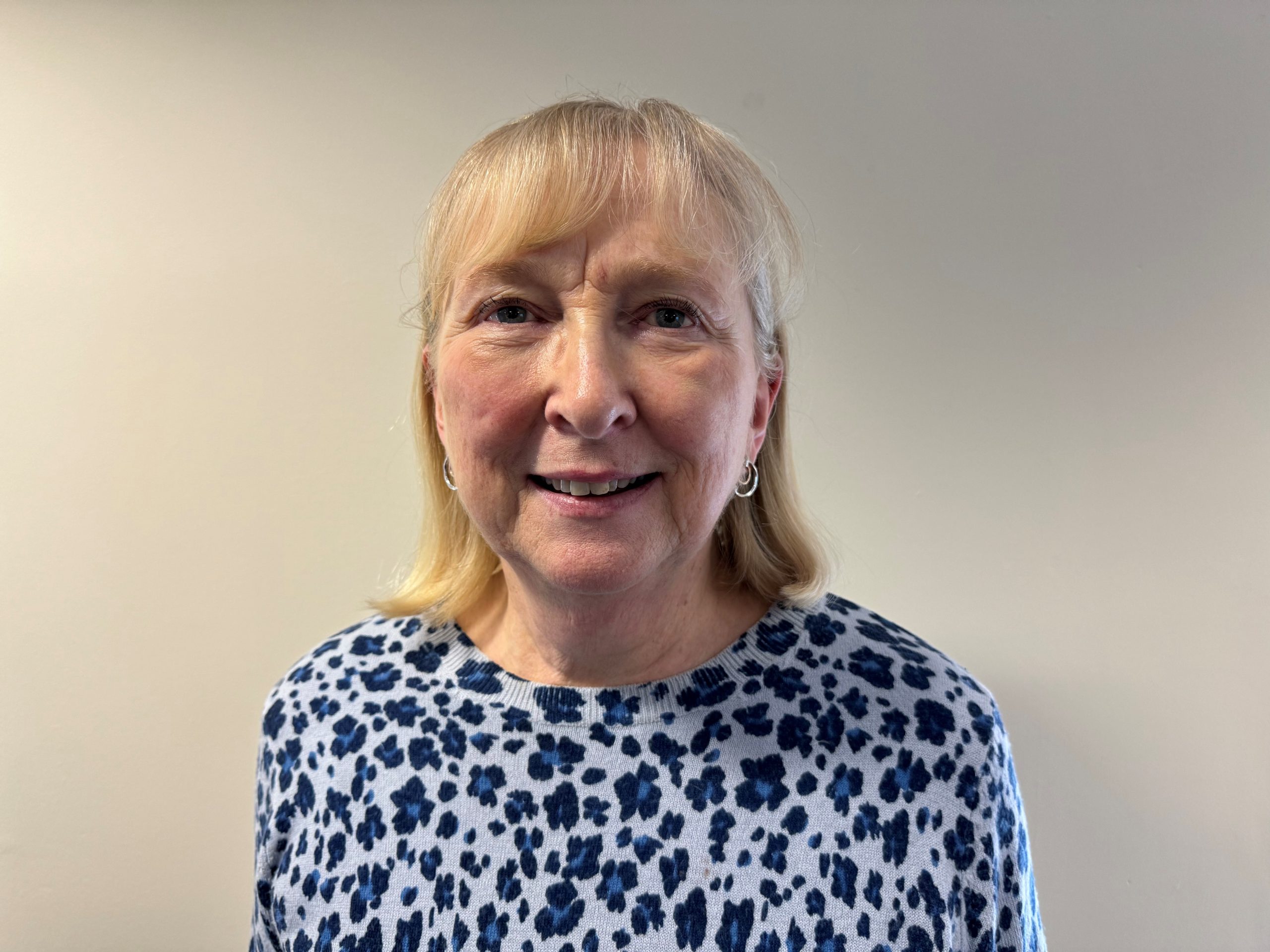 A woman with blonde hair wearing a colourful floral top